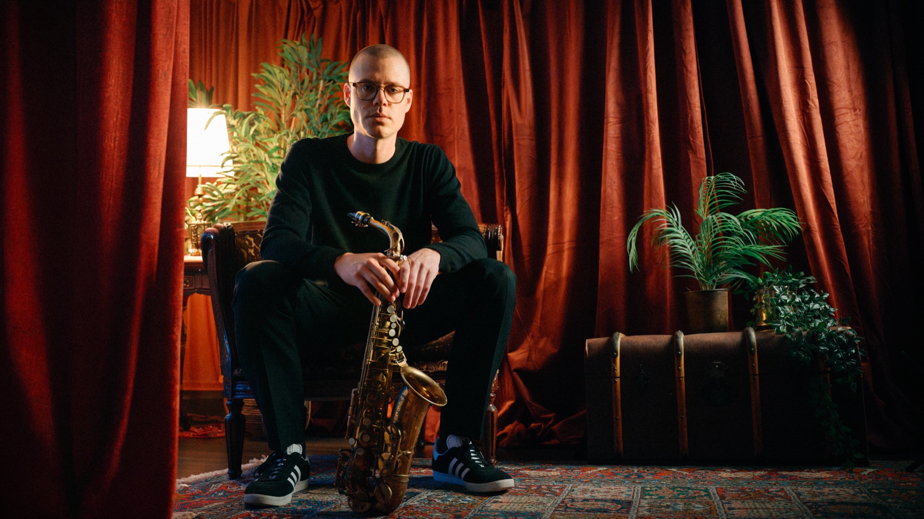 Johan Christoffersson seated with his saxophone in front of curtains